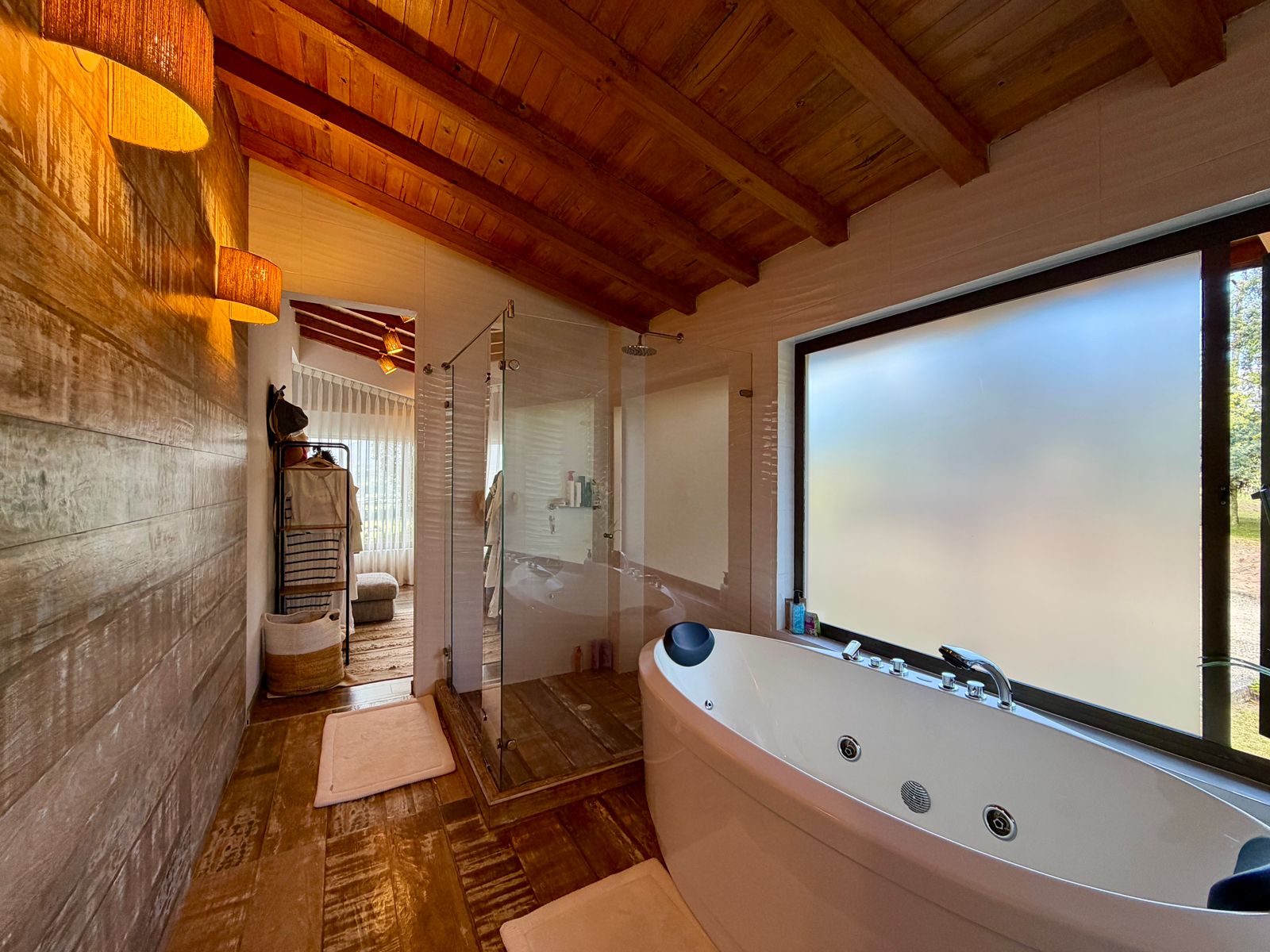 Baño cálido con tina de hidromasaje, ducha y techo en madera