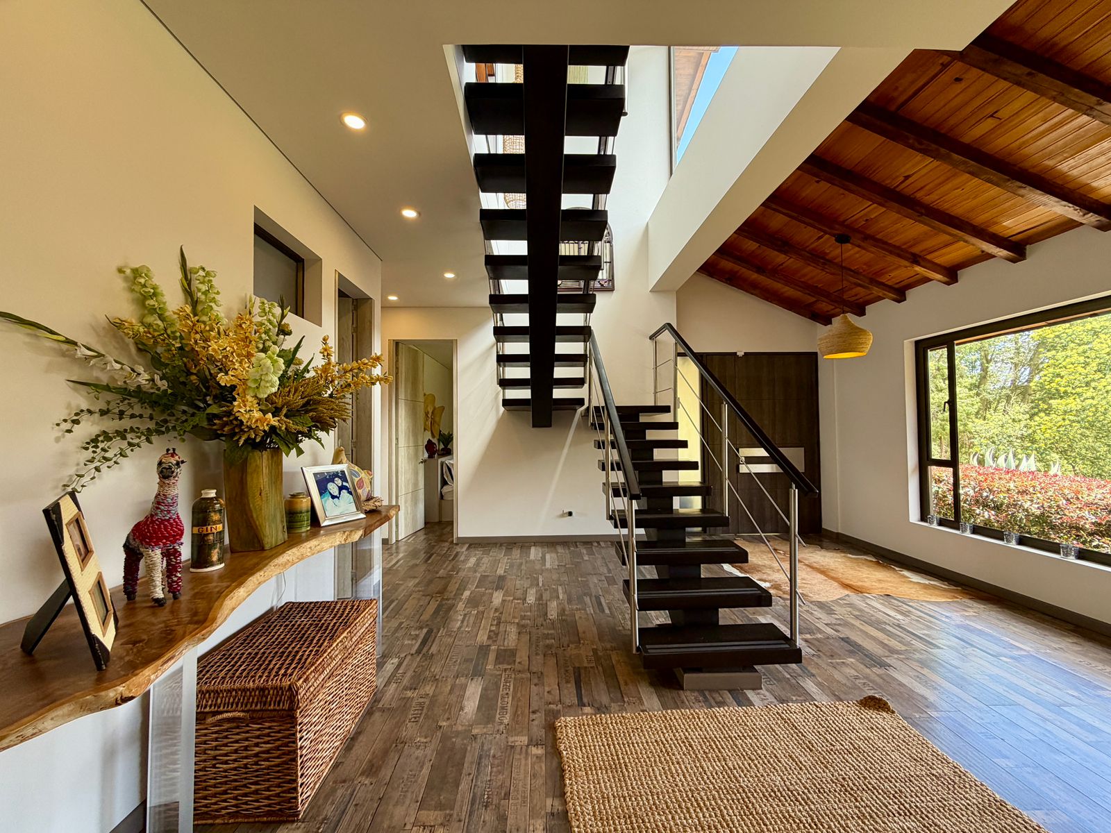 Hall interior de doble altura con escalera contemporánea y acabados en madera