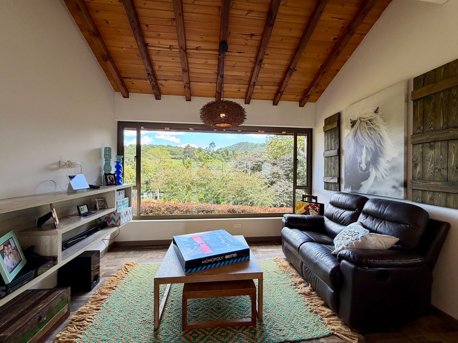 Sala de televisión luminosa con gran ventanal hacia los jardines de El Encanto